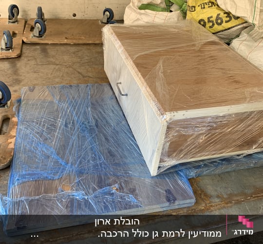 ארגזים וציוד עטופים בניילון על משטח הובלה